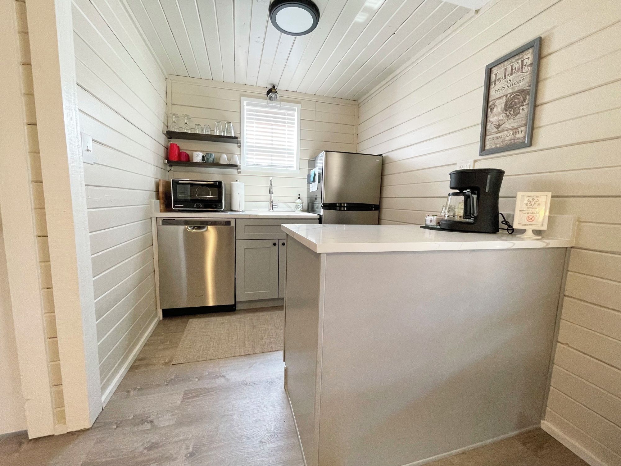 A compact kitchen with a stainless steel refrigerator, a microwave, and a coffee maker.