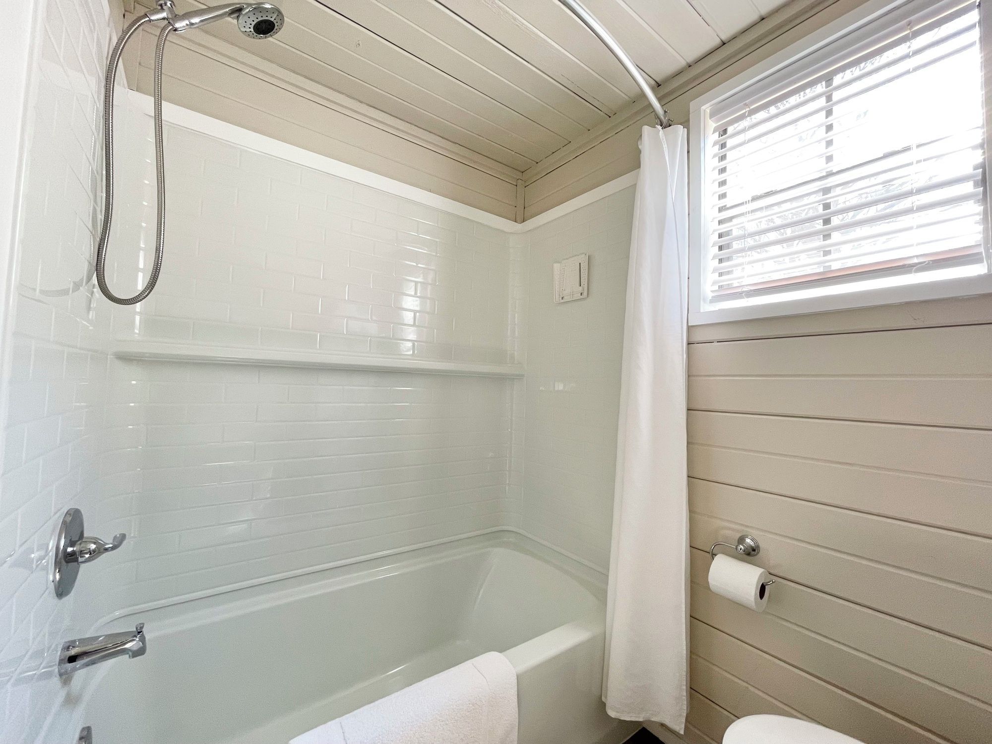 A bathroom with a bathtub, shower, and toilet.