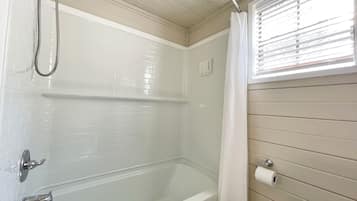 A bathroom with a bathtub, shower, and toilet.
