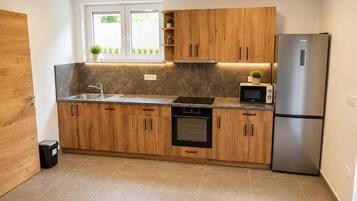 Una cocina moderna con armarios de madera, un refrigerador de acero inoxidable, un microondas y un horno empotrado.