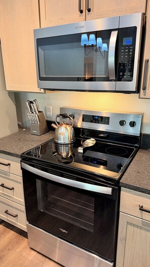 A kitchen with a stainless steel microwave, a kettle, and an oven. - "The Wilson Cabin" Cozy Accommodation on the River (Norfork)