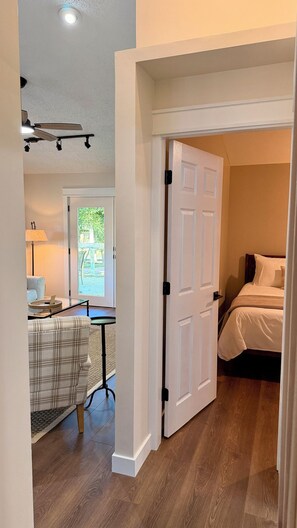 A hotel room with a bed, a desk with a lamp, a chair, and a view of the outdoors through a door. - "The Wilson Cabin" Cozy Accommodation on the River (Norfork)