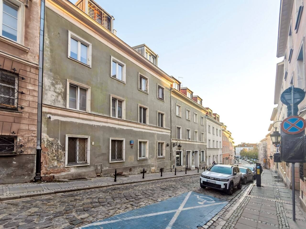 Una stretta via fiancheggiata da edifici, un percorso in pietra e un'auto parcheggiata.