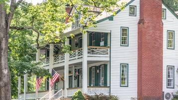 Een gebouw met twee verdiepingen, een balkon, een bakstenen schoorsteen en Amerikaanse vlaggen.