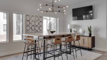 Une cuisine moderne dotée d’un îlot central, de tabourets de bar, d’une table à manger et d’un téléviseur fixé au mur.