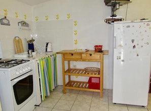 A kitchen with a stove, oven, and refrigerator, a wooden shelf unit, and a tiled backsplash with yellow leaf decals. - Two bedroom Spacious Apartment with a Sea View (Zubovići)