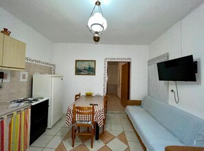 Ett kompakt bostadsutrymme med ett litet kök, en matplats och en sittgrupp med tv.