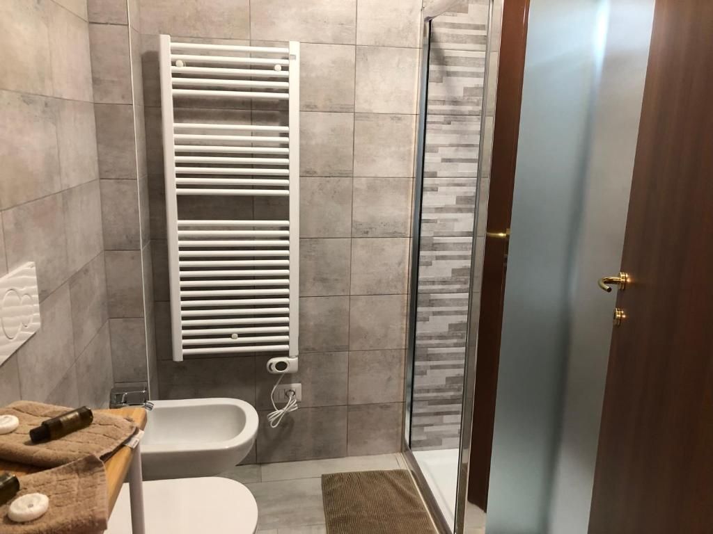Un bagno con vasca, WC, portasciuga e cabina doccia in vetro.