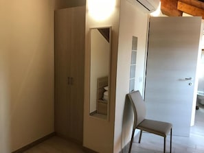 A room with a wardrobe, a chair, and a door. - B&B da Mary  (Magenta)