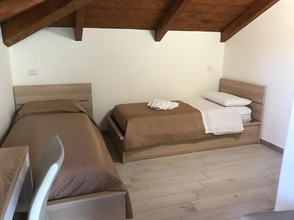 A room with two beds, wooden headboards, and a wooden floor.
