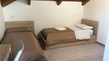 A room with two beds, wooden headboards, and a wooden floor.