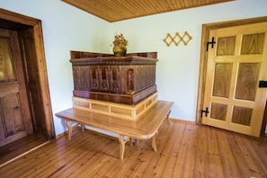 Una habitación con un banco de madera, una puerta de madera y un objeto decorativo en la pared.