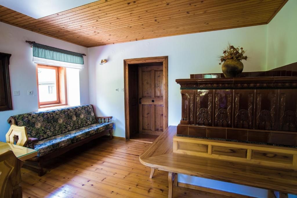 Una habitación con techo de madera, un banco de madera, un sofá, una puerta de madera y una ventana con cortina.