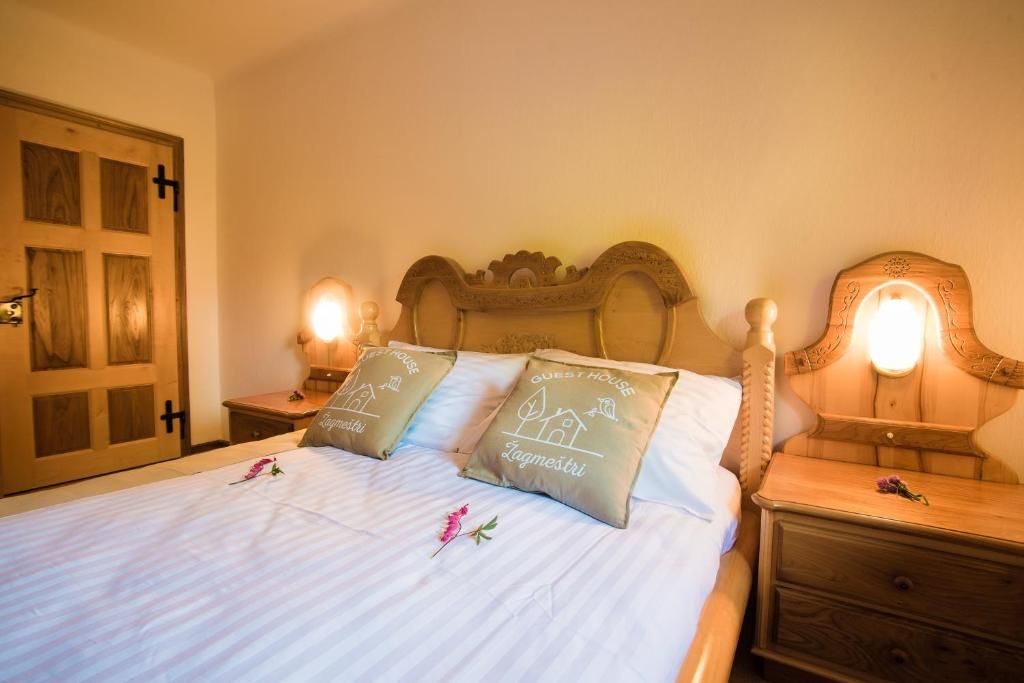 A bed with two pillows, a wooden headboard, bedside tables with lamps, and a door with a cross symbol.
