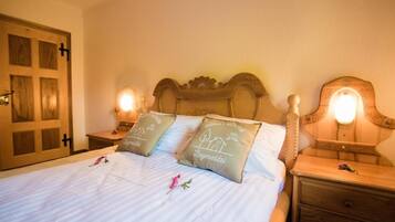 A bed with two pillows, a wooden headboard, bedside tables with lamps, and a door with a cross symbol.