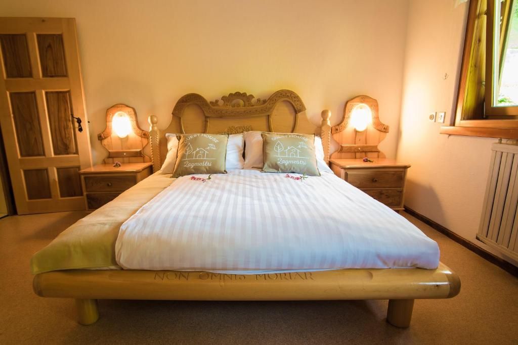 A bed with a headboard, two bedside tables with lamps, and a window with curtains.
