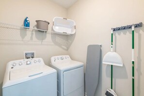 A laundry area with two washing machines, a drying rack, a mop, and a laundry basket. - Stylish 3BR Condo Near Disney & Resort Fun (Davenport)