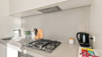 A modern kitchen with a gas stove, a coffee maker, and a box of Biscuits.