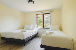 Ein Zimmer mit zwei Betten, einem Fenster und einer Deckenleuchte.