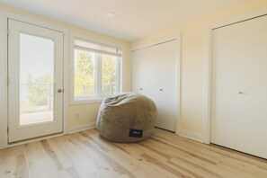 Ein Zimmer mit einem großen Sitzsack, einer Tür und einem Fenster mit Rollläden.