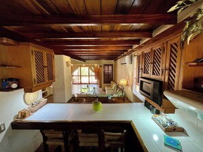 Une cuisine dotée de meubles en bois, d’un four à micro-ondes et d’un coin repas avec une table et des chaises.
