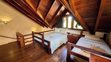 Ein Schlafzimmer im Loft-Stil mit Holzbalken und schrägem Dach, ausgestattet mit zwei Betten.