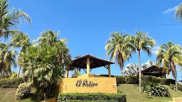 A sign with 'El Retiro' written on it, surrounded by palm trees and a clear blue sky.
