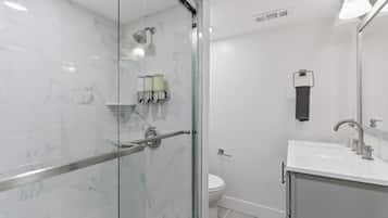 Un baño moderno con cabina de ducha de vidrio, inodoro y lavabo con espejo.