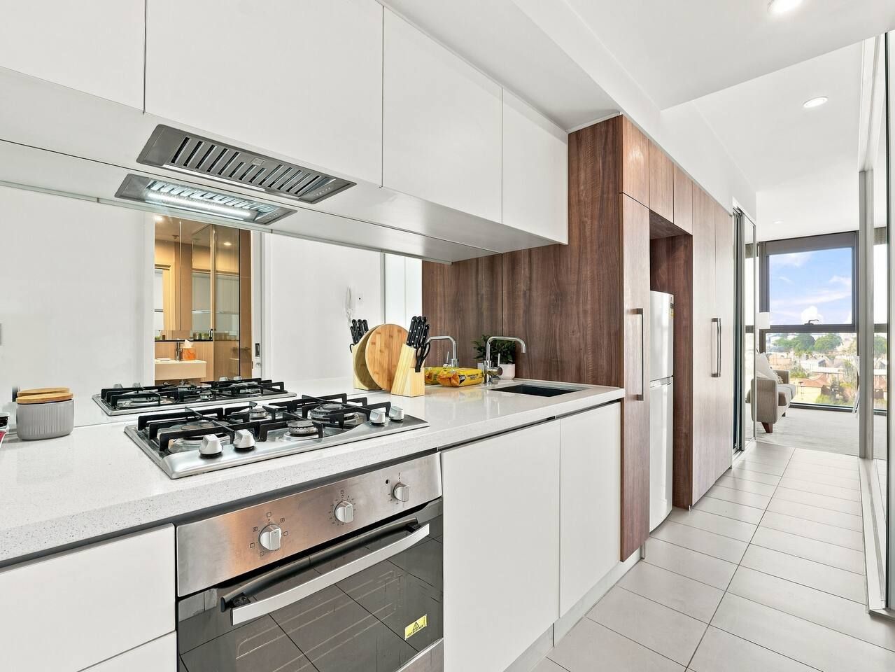 Una cocina moderna con estufa a gas, electrodomésticos de acero inoxidable y vistas al exterior.