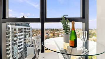 Una habitación moderna con una mesa de vidrio, una botella de champán y una planta en maceta.