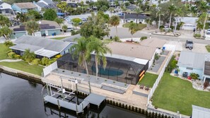 A residential area with a large house featuring a swimming pool, a covered outdoor area, and a dock extending into a body of water. - Waterfront Escape Heated
Pool Kayaks & Boat Lift (Apollo Beach)