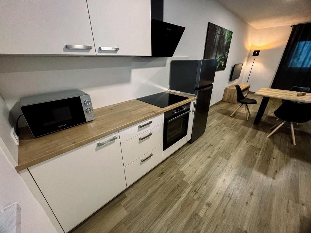 Una cocina compacta con gabinetes blancos, microondas, horno y refrigerador.