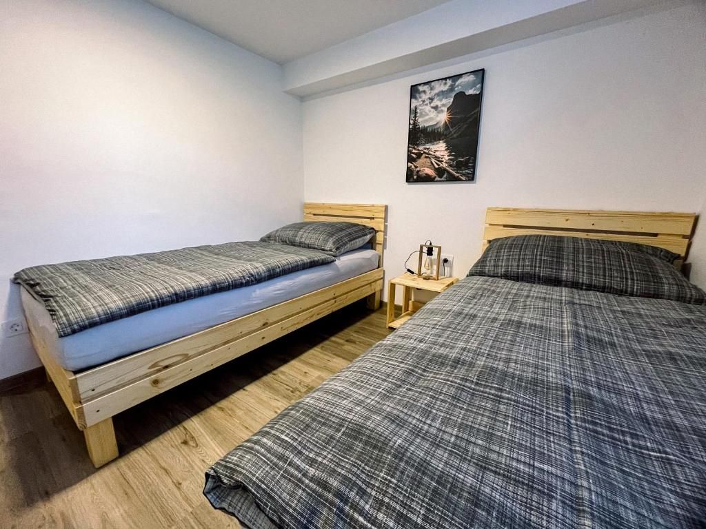 Una habitación con dos literas de madera, una mesita de noche con lámpara y un cuadro en la pared.
