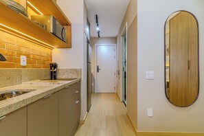A kitchen with a granite countertop, stainless steel sink, and wooden cabinets. - Nex One Faria Lima NR (São Paulo)