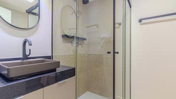 A modern bathroom with a glass-enclosed shower, a sink with a faucet, and a mirror.