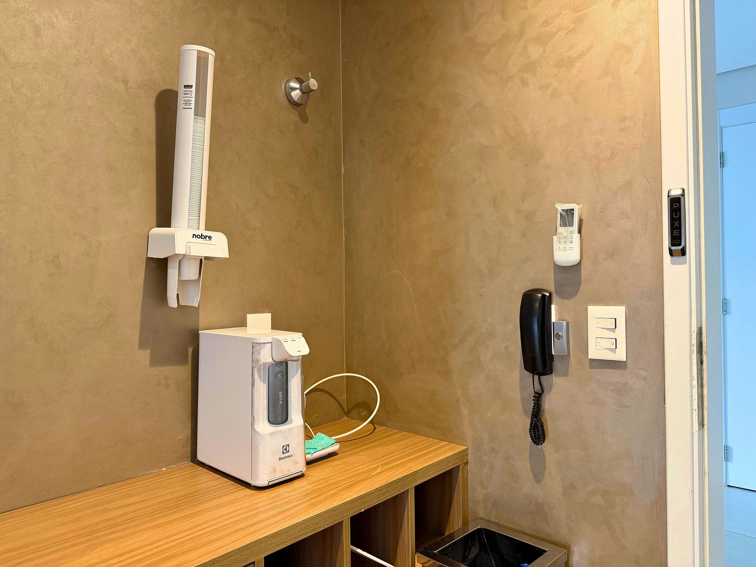 Casa de banho com dispensador de toalhas, telefone e lixeira.
