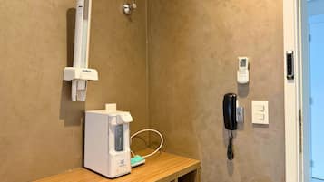 Casa de banho com dispensador de toalhas, telefone e lixeira.