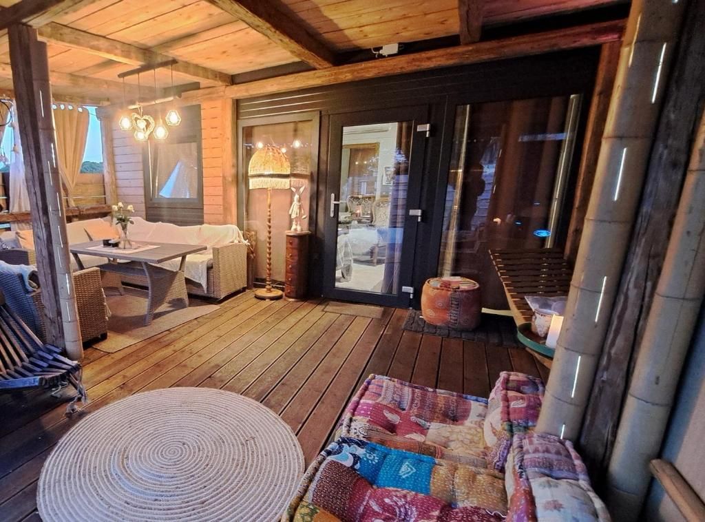 A wooden deck with a sofa, a table, and a lamp.