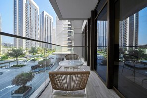 A balcony with a view of a cityscape, a round table, and a wicker chair. - Elegant 1BR Retreat in Palace Residences | Creek (Dubai)