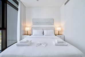 A hotel room with a large bed, two bedside lamps, a window with curtains, and a painting on the wall. - Chic 1BR Escape in Palace Residences | Creek (Dubai)