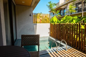 Un espace piscine comprenant une chaise, une petite piscine et une clôture en bambou.