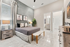 A modern bedroom with a bed, bedside tables, a bench, and a large mirror. - Paradiso Grande 15br Suites, Pool & Themed Rooms (Orlando)