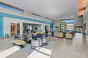 A spacious lobby with a high ceiling, modern furniture, and large windows providing natural light. - Paradiso Grande 15br Suites, Pool & Themed Rooms (Orlando)
