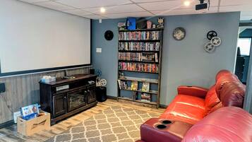 A home theater room with a large screen, a bookshelf, a red leather couch, and a wooden entertainment unit.