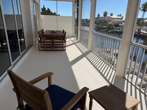 A balcony with a table and chairs, overlooking a body of water and buildings. - Salty Serenity | Your Hernando Beach Escape (Hernando Beach)
