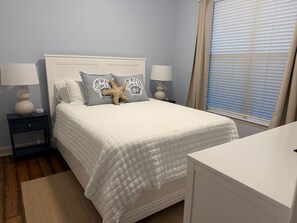 A bedroom with a bed, nightstands, a desk, and a window with blinds. - Salty Serenity | Your Hernando Beach Escape (Hernando Beach)