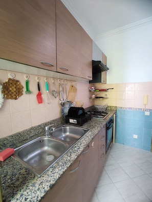 A kitchen with granite countertops, stainless steel sink, wooden cabinets, and various kitchen utensils hanging on the wall. - Tranquil 2-bedroom apartment in vibrant Casablanca neighborhood (Casablanca)