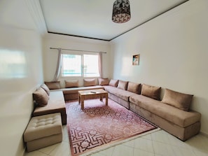 A living room with a sectional sofa, a coffee table, and a patterned rug. - Tranquil 2-bedroom apartment in vibrant Casablanca neighborhood (Casablanca)