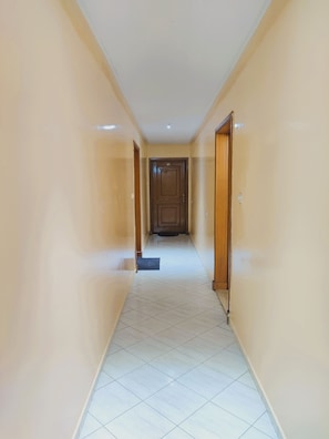 A corridor with a door at the end, tiled floor, and plain walls. - Tranquil 2-bedroom apartment in vibrant Casablanca neighborhood (Casablanca)