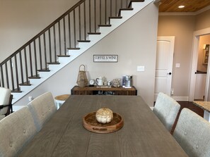A dining area with a wooden table, chairs, a decorative pumpkin centerpiece, and a staircase with a 'Coffee & Wine' sign. - New Listing: Modern Mountain Farmhouse with Views (Union Mills)